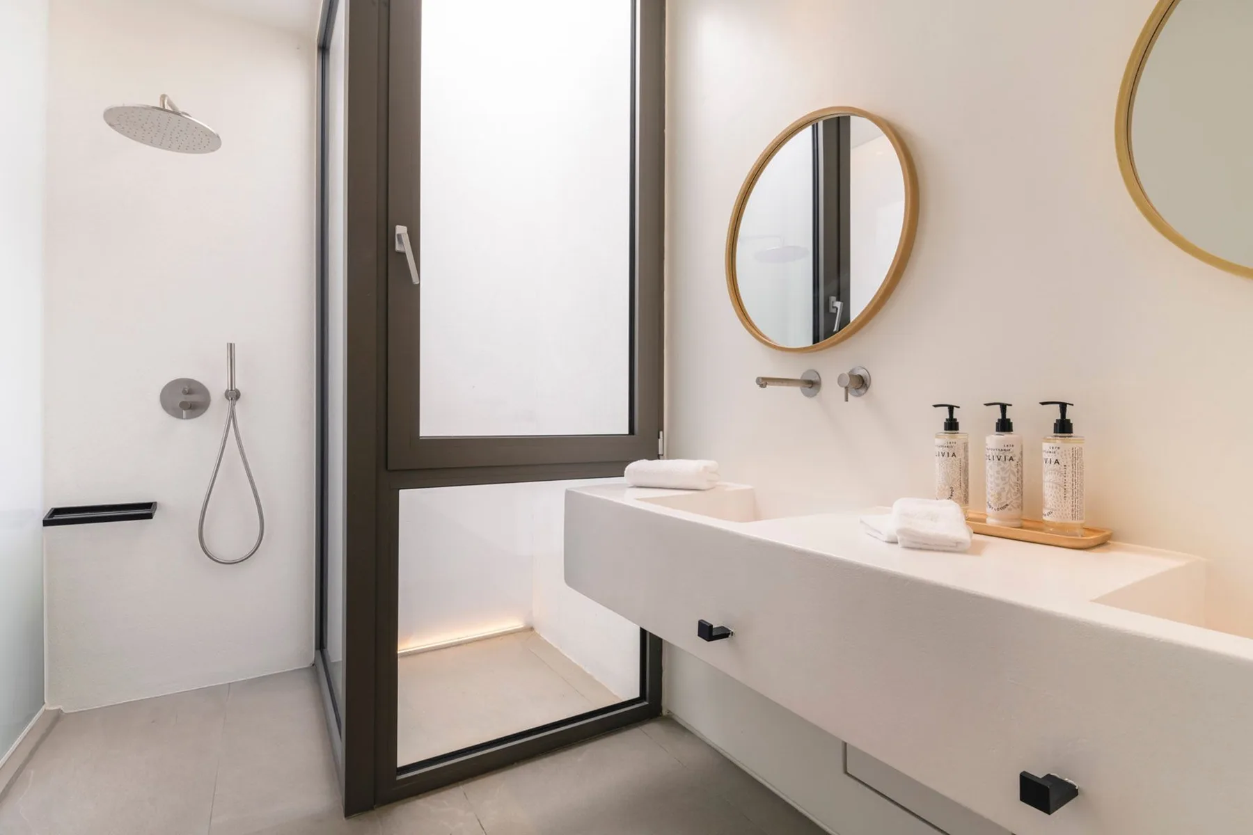 A modern bathroom with a walk-in shower and a long white vanity.