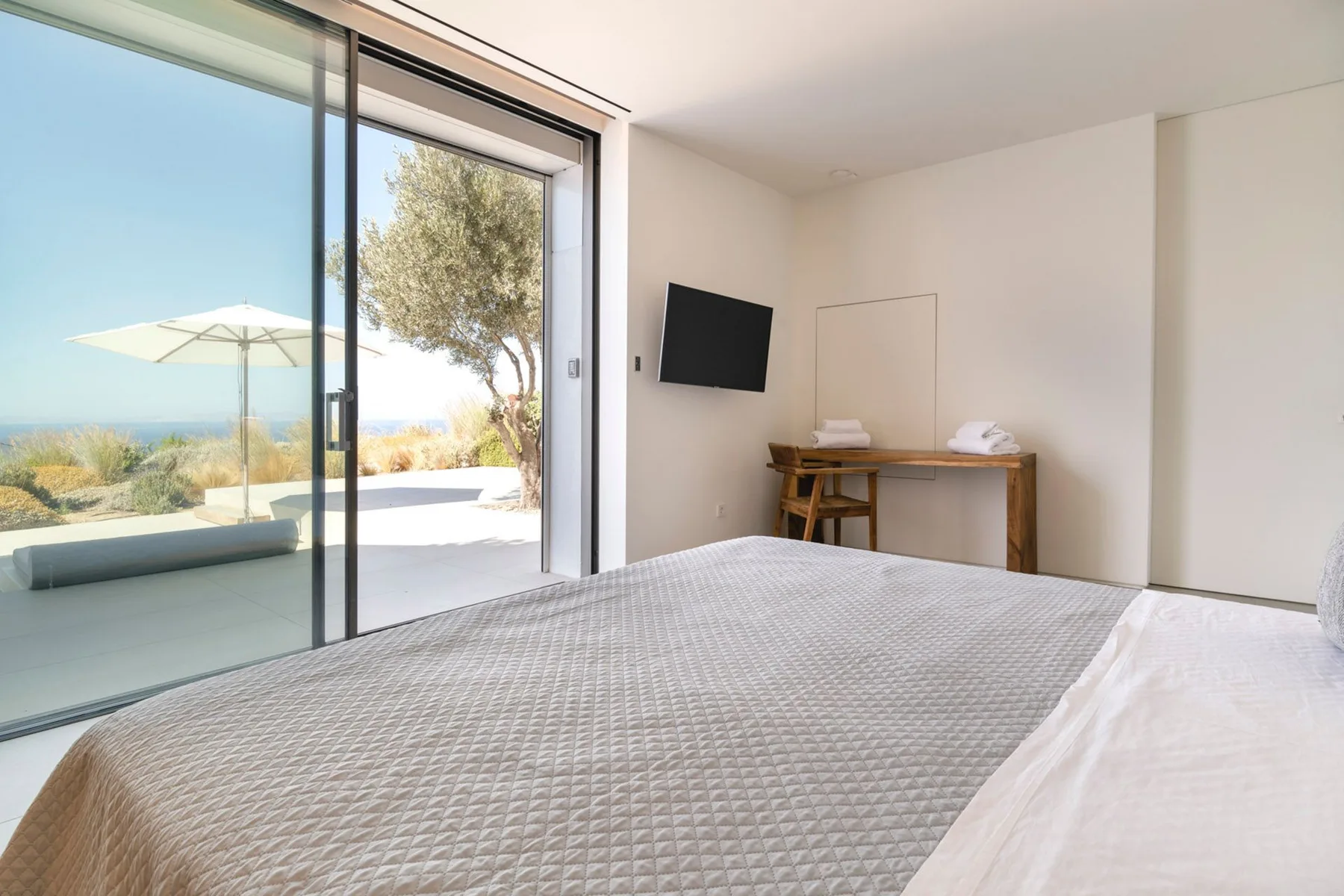 A bright bedroom opens onto a patio through large sliding glass doors.