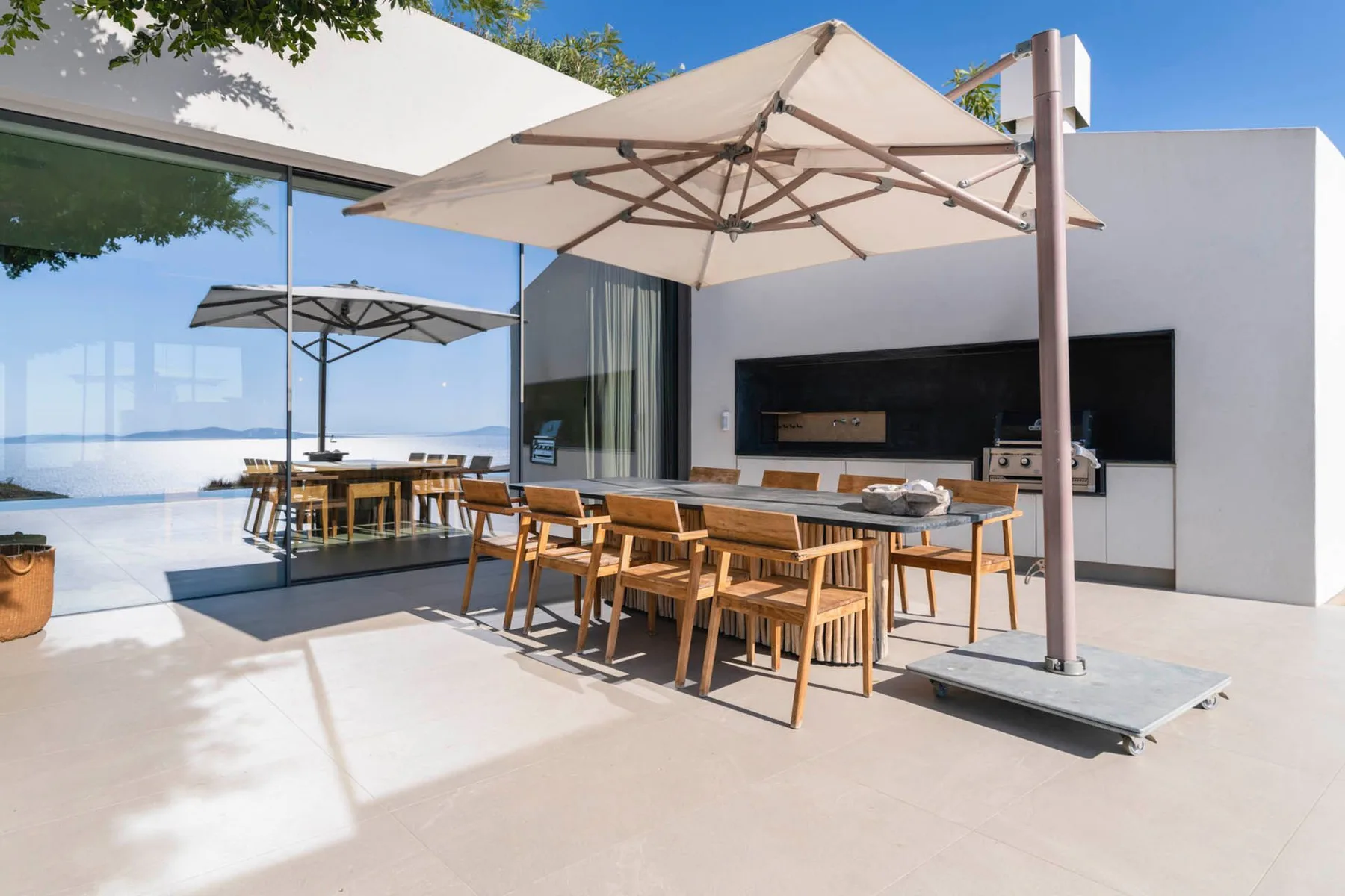 An outdoor dining area with a wooden table beneath a large patio umbrella.