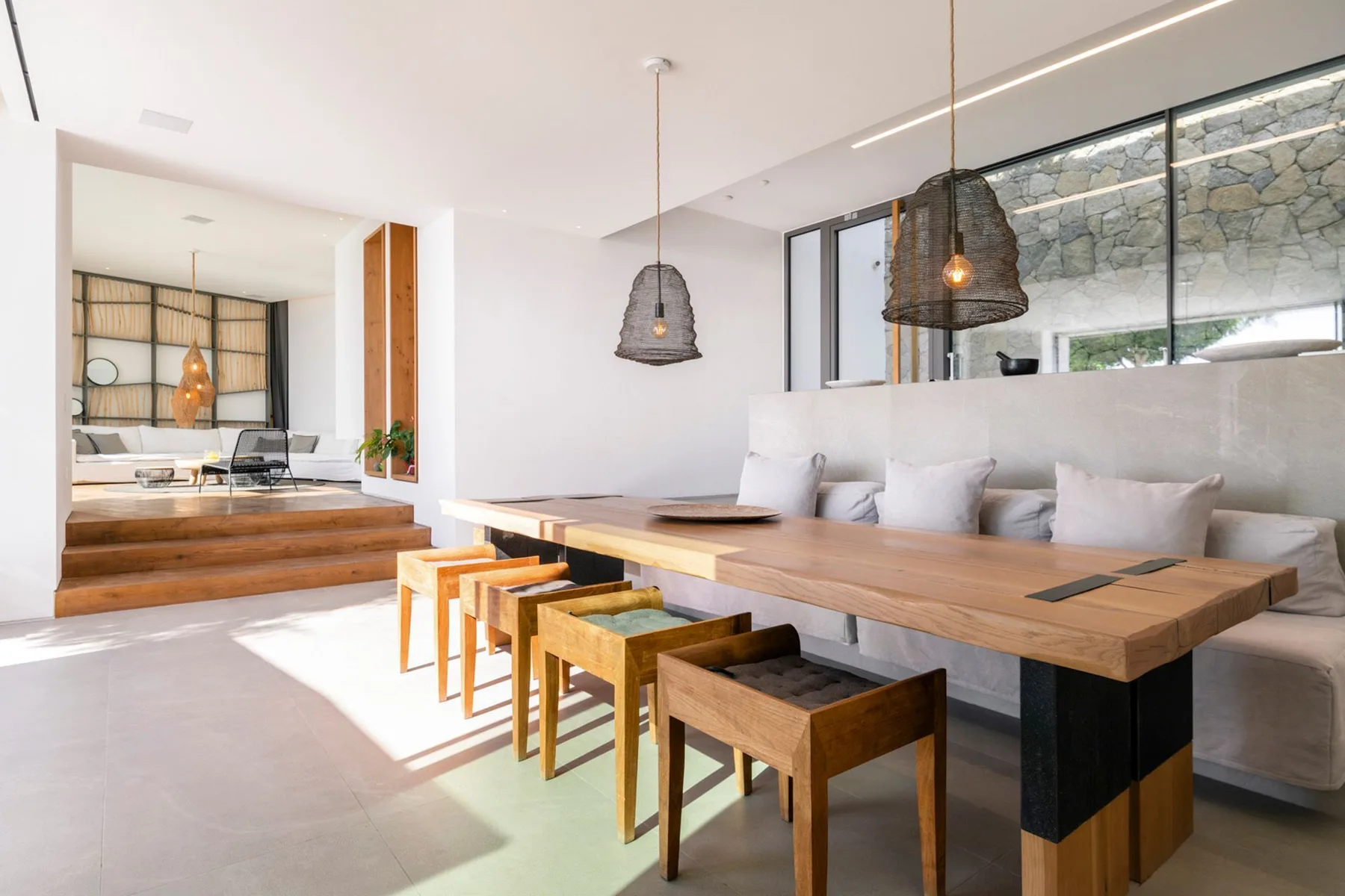 A dining area with a long wooden table and seating beside a lounge.