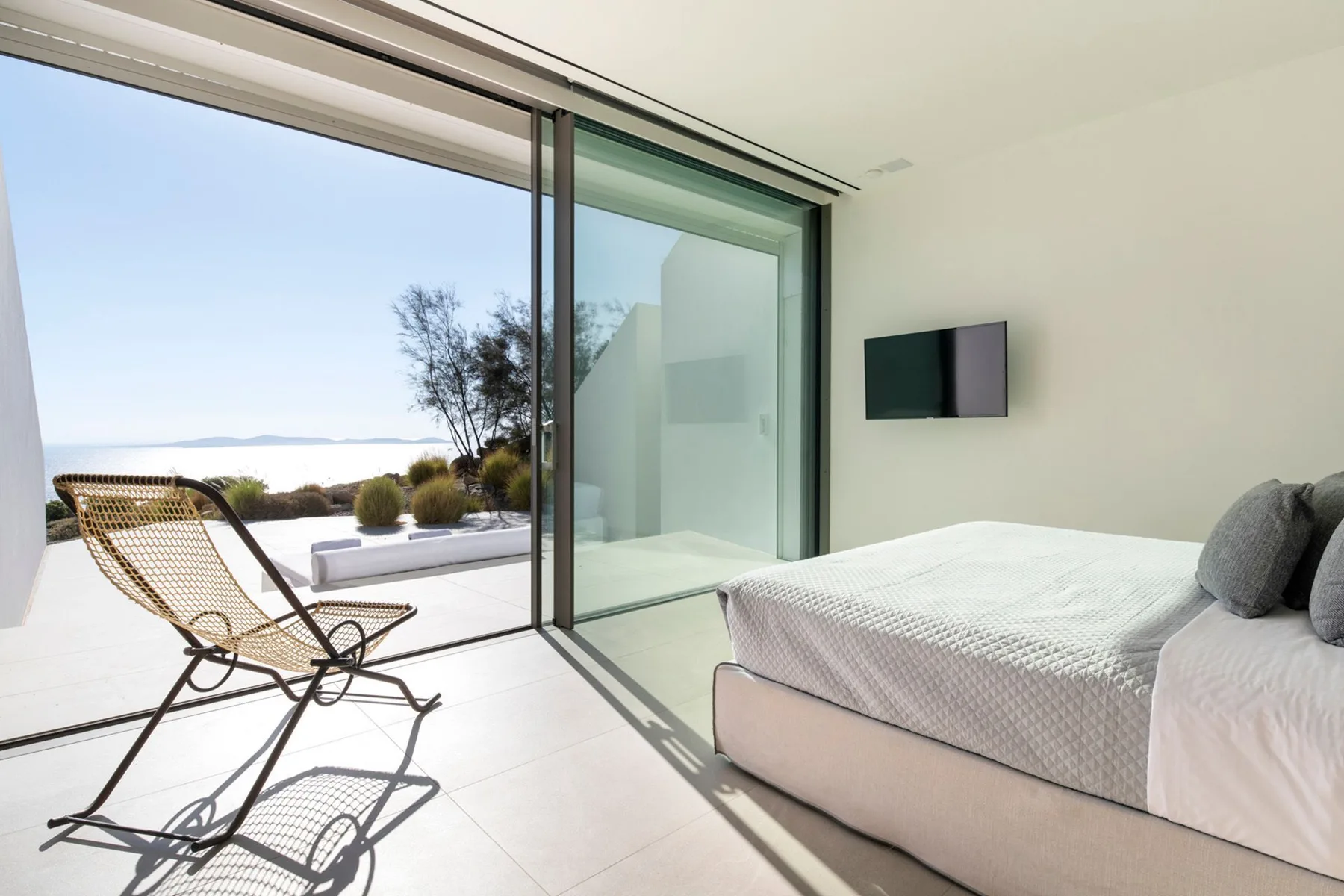 A bedroom with a bed beside sliding glass doors opening onto a patio.
