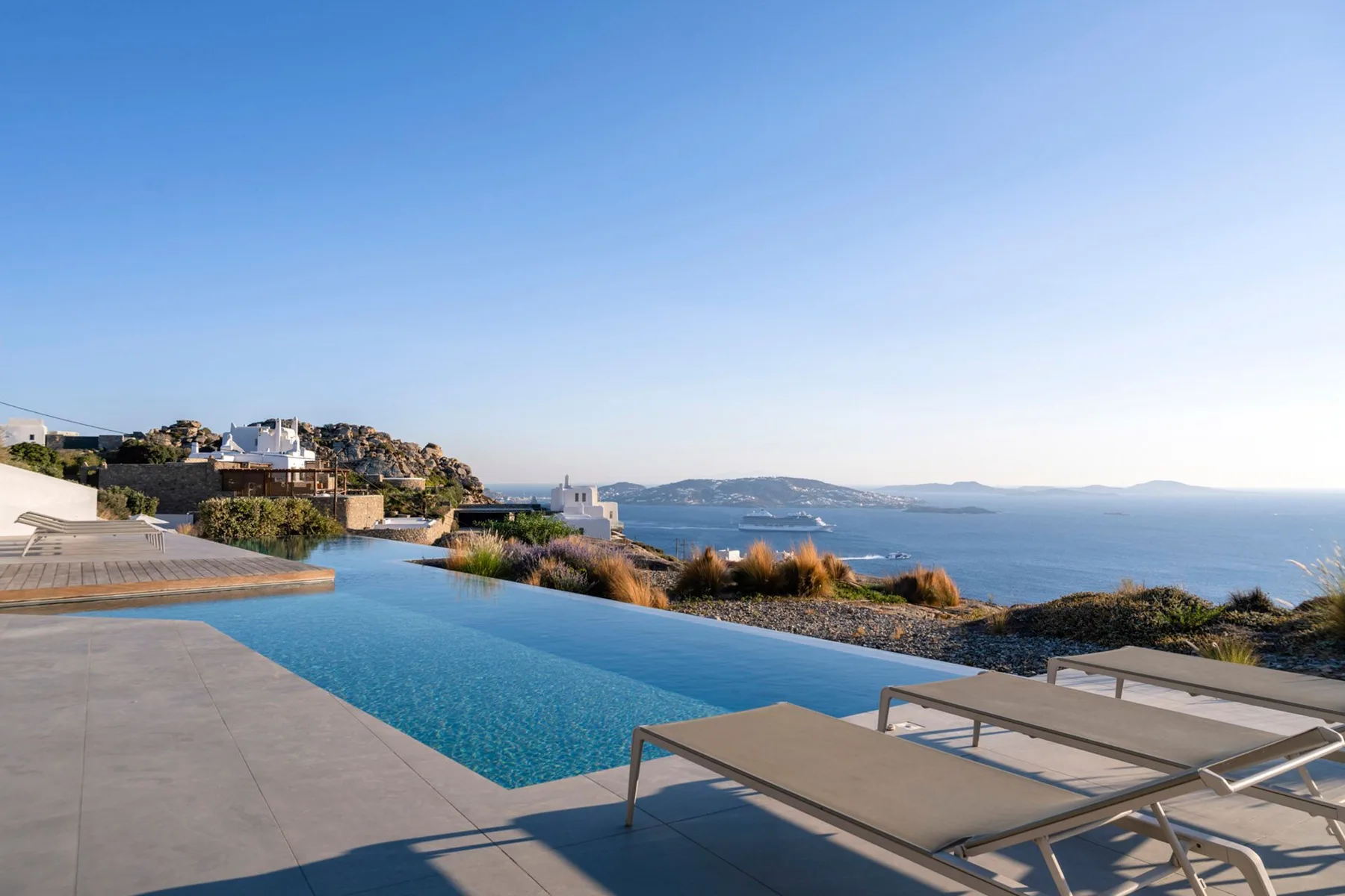 An infinity pool overlooks the sea, with lounge seating on the terrace.
