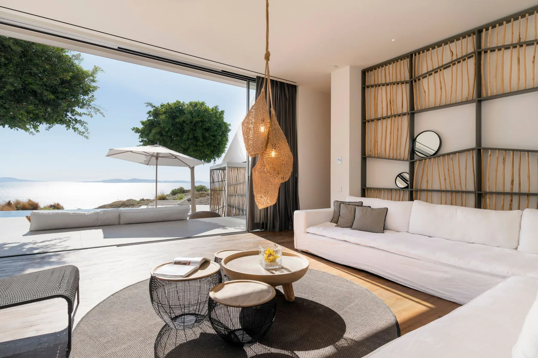 A bright living room opens onto a patio with seating and a view of the water.