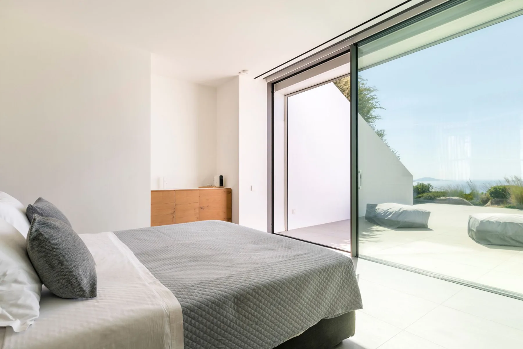 A bright bedroom with a bed beside a large sliding glass door.