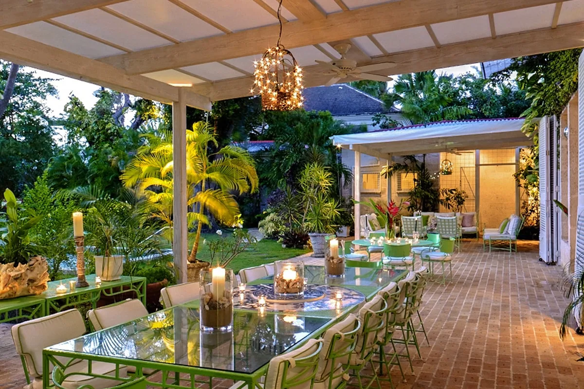 Un patio cubierto con mesas de vidrio y abundantes plantas.