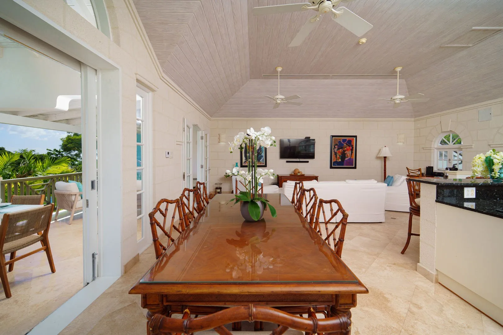 Un comedor con una larga mesa de madera y asientos, abierto a una sala de estar luminosa.