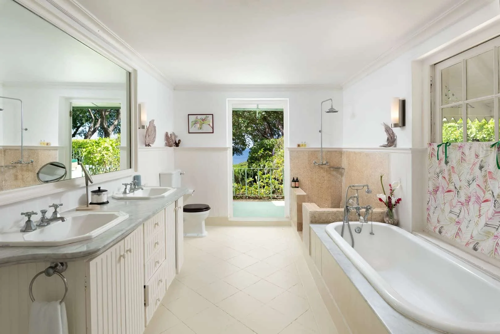 A bright bathroom with a bathtub, vanity, and glass doors opening to greenery.