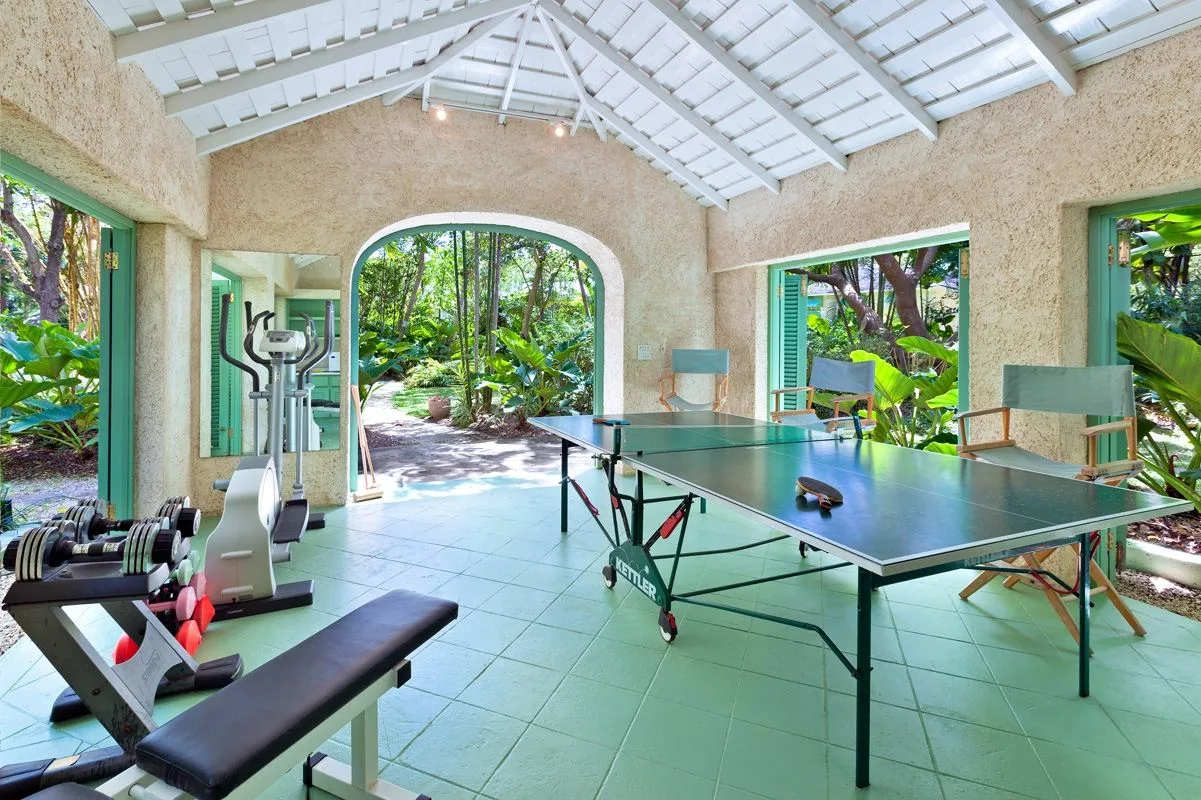 An open indoor recreation area has a table tennis table and exercise equipment.