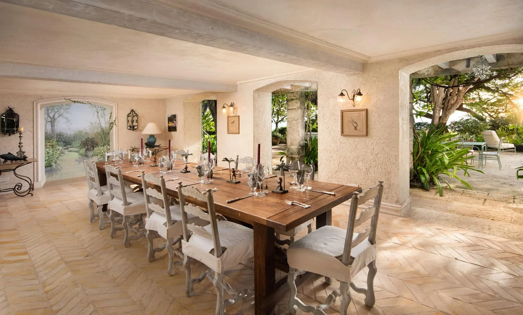 A dining room with a long wooden table and seating beside open archways.