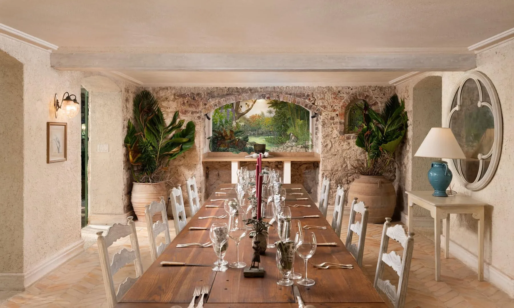 A rustic dining room with a long wooden table set beneath a stone arch.