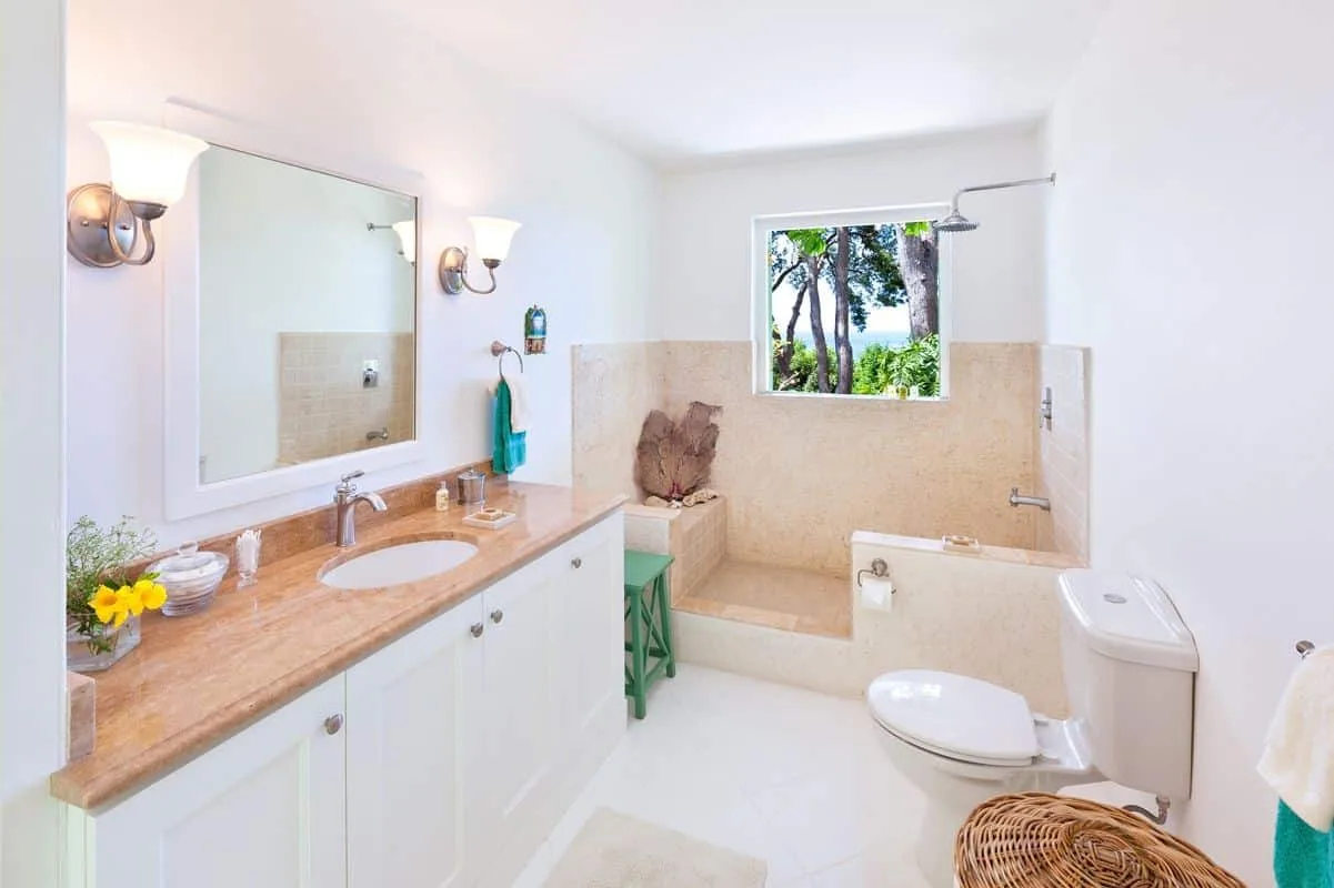 A bright bathroom with a long vanity, sink, and bathtub beneath a window.