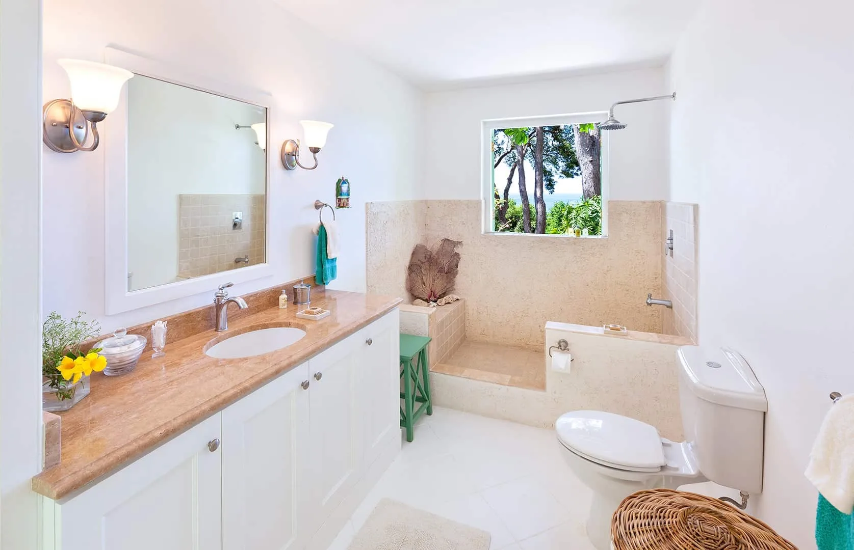 A bright bathroom with a long vanity and a bathtub beneath a window.