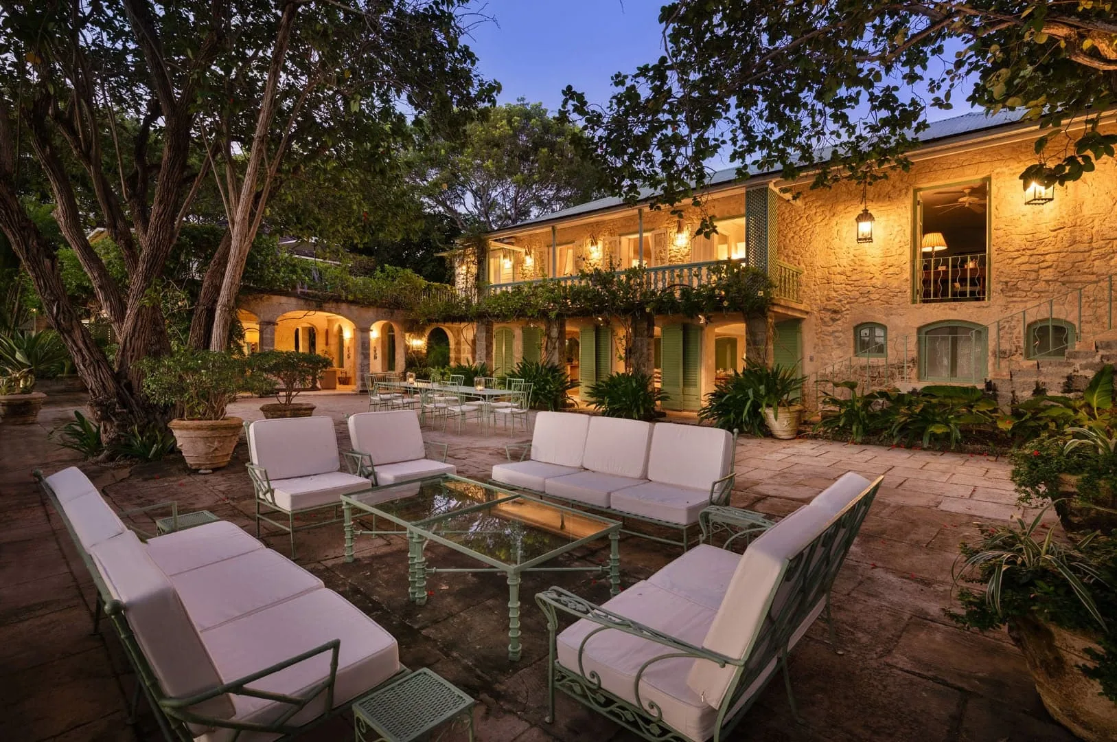 An outdoor courtyard lounge with cushioned seating and a warmly lit building.