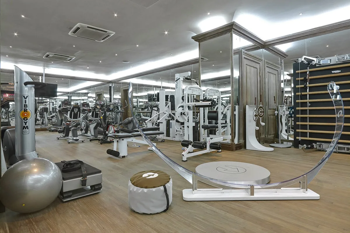 Un gimnasio con máquinas de ejercicio, pesas y una pared de espejos.