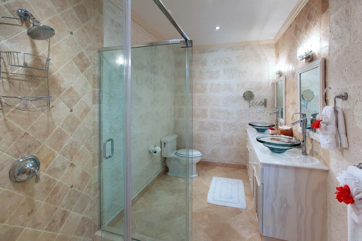 Un baño con azulejos, una ducha de vidrio y un lavabo con mueble.