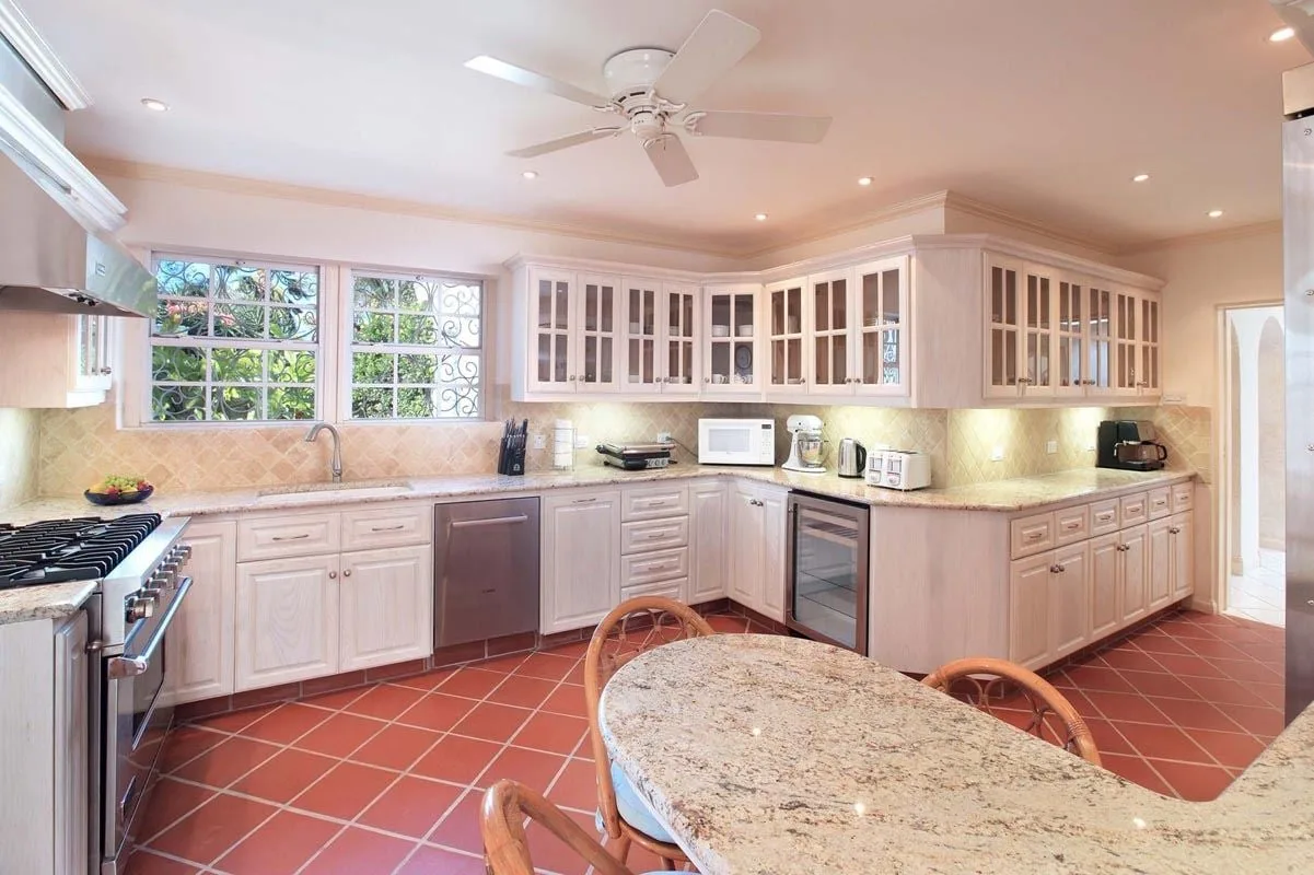 Una cocina luminosa con gabinetes claros, piso de baldosas e isla central.