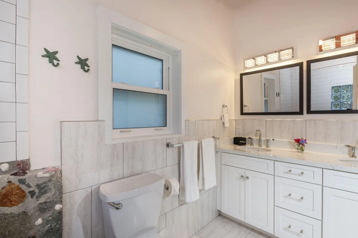 Un baño luminoso con una ventana, un lavabo con mueble y espejos.