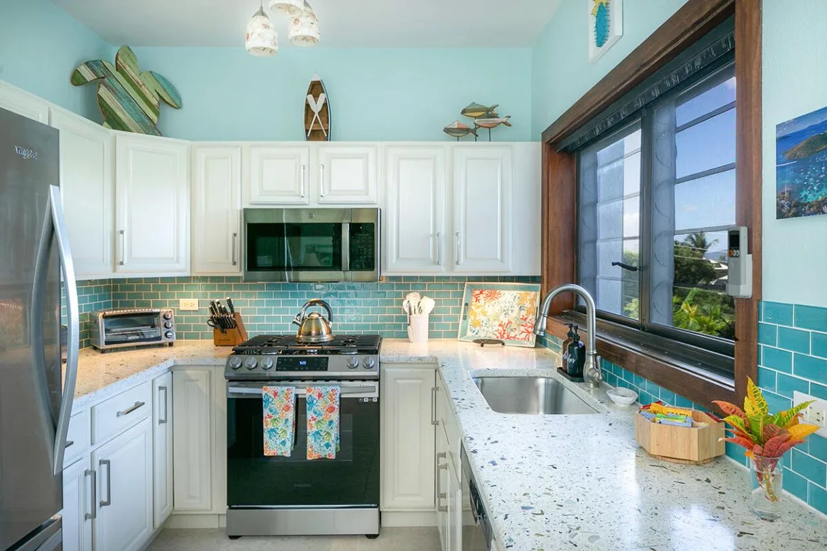 Una cocina luminosa con gabinetes blancos, una estufa y una ventana sobre el fregadero.