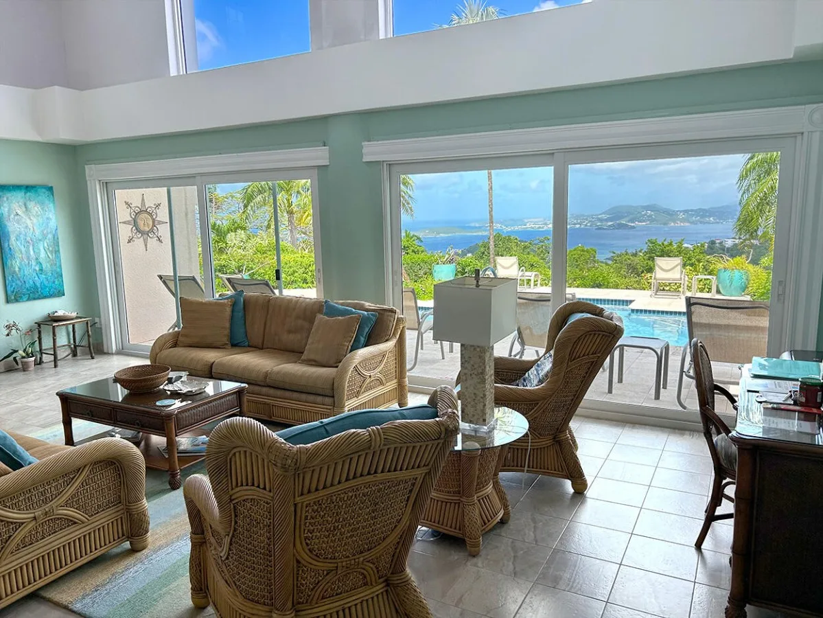 A bright living room opens onto a patio with a pool and coastal views.