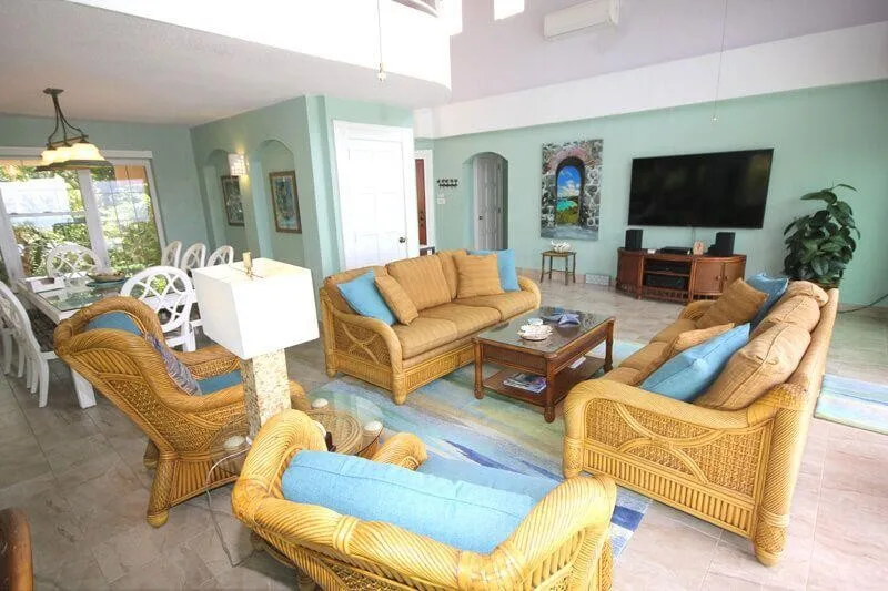 A living room with wicker seating arranged around a coffee table and television.