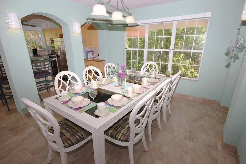 A dining room with a long table set beside a large window.