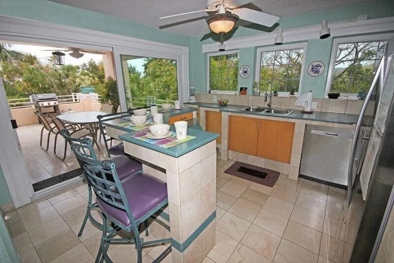 A bright kitchen with a central counter and windows overlooking an outdoor patio.