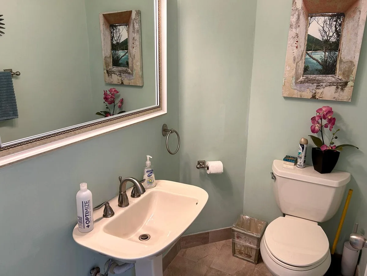 A bathroom with a sink, toilet, and a framed picture on the wall.