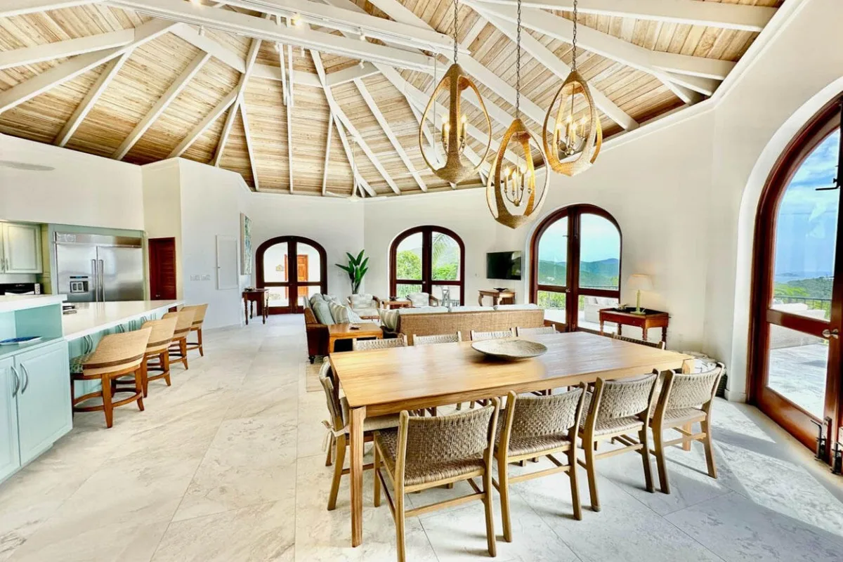 A bright dining area with wooden tables, chairs, and arched windows.