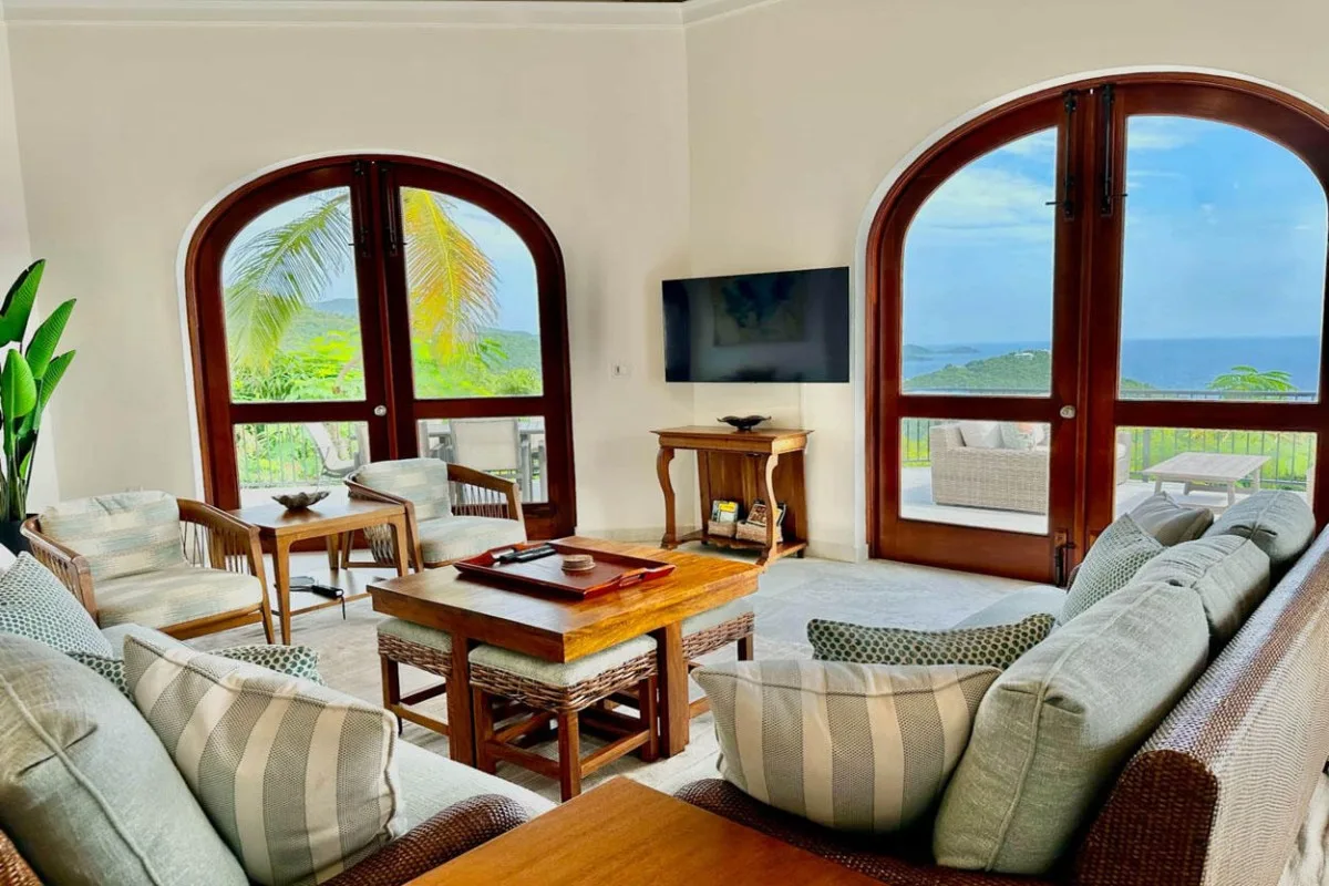A bright living room with seating and a coffee table beside large arched windows.