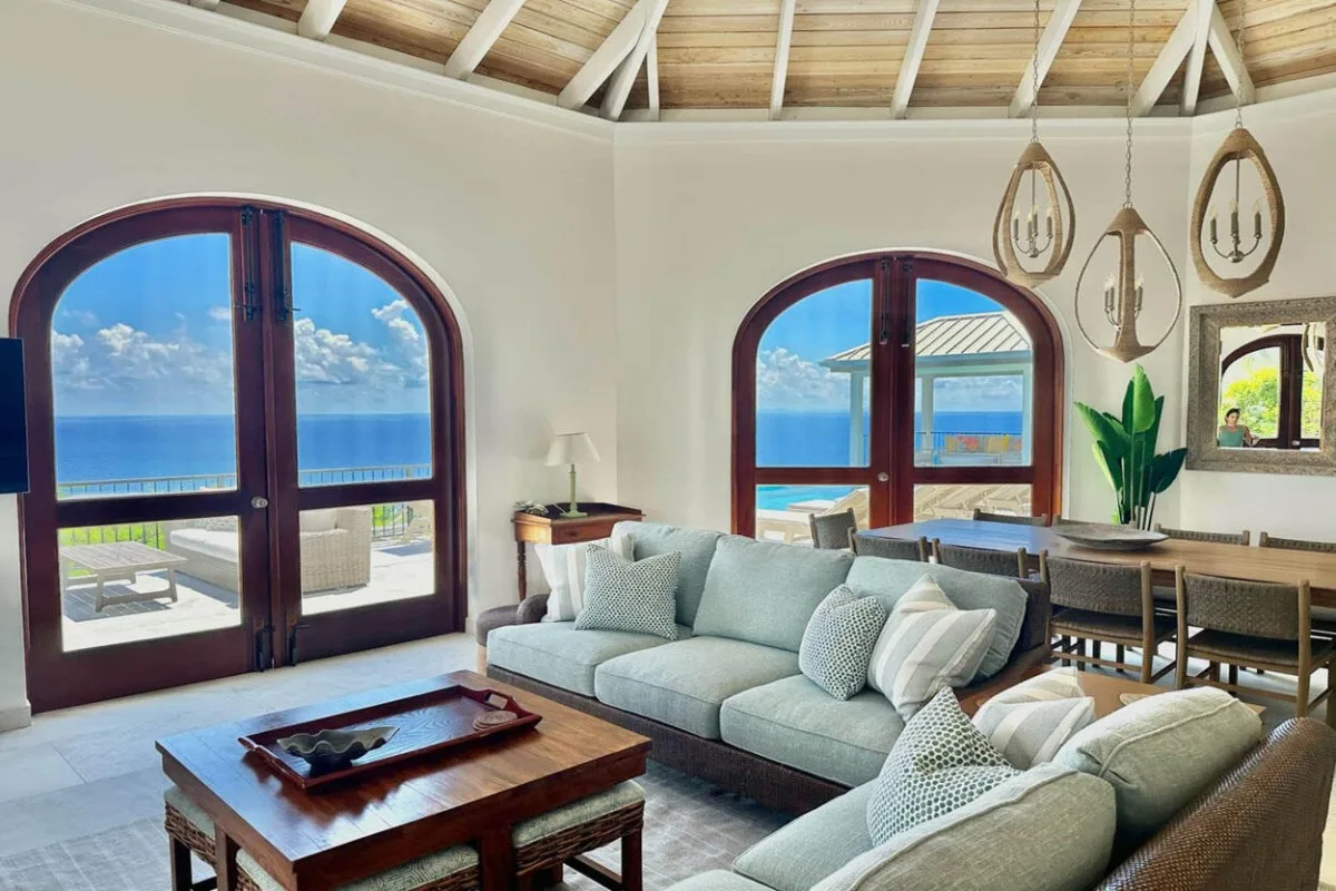 A bright living room with seating, arched windows, and ocean views.