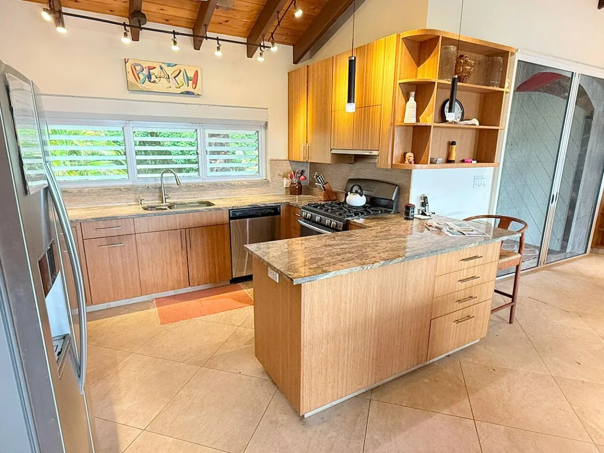 A kitchen with wooden cabinets, a central island, and windows above the sink.