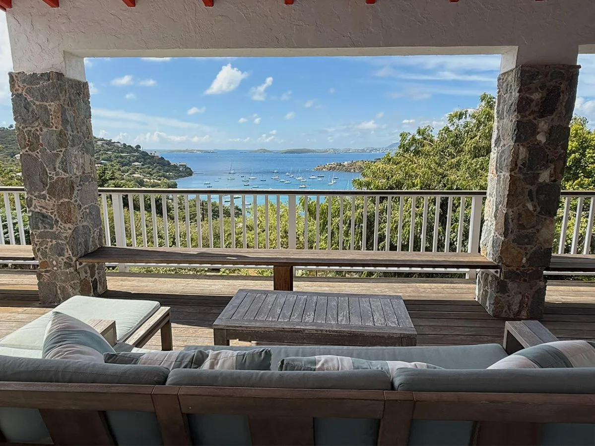 A covered outdoor seating area overlooks the bay and surrounding green hills.