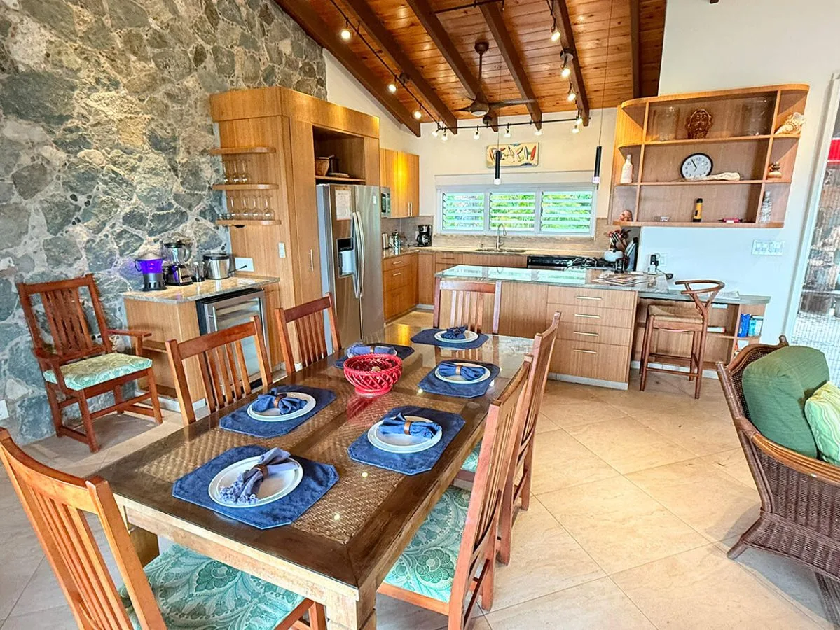 A dining and kitchen area with a set table and wooden cabinetry.