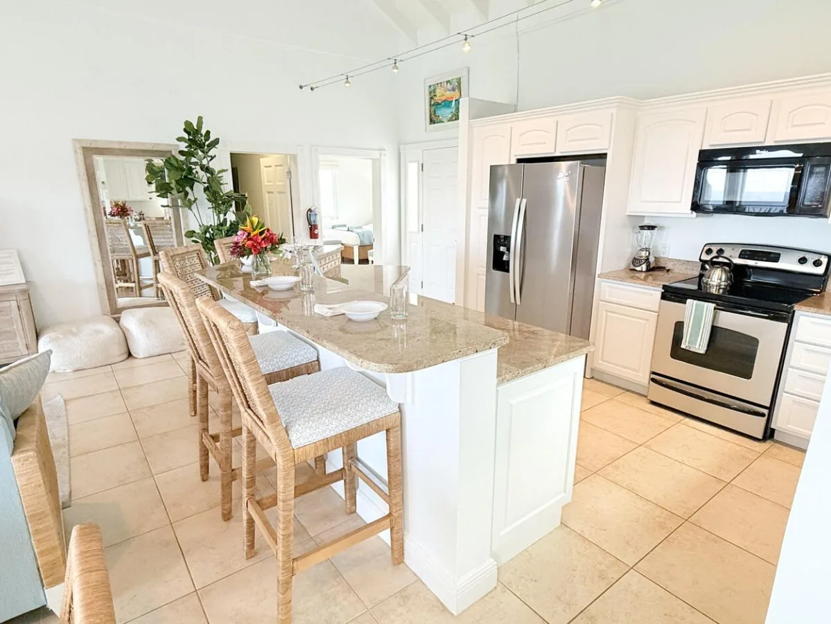 Una cocina y comedor luminosos cuentan con una isla central y una mesa con asientos tejidos.