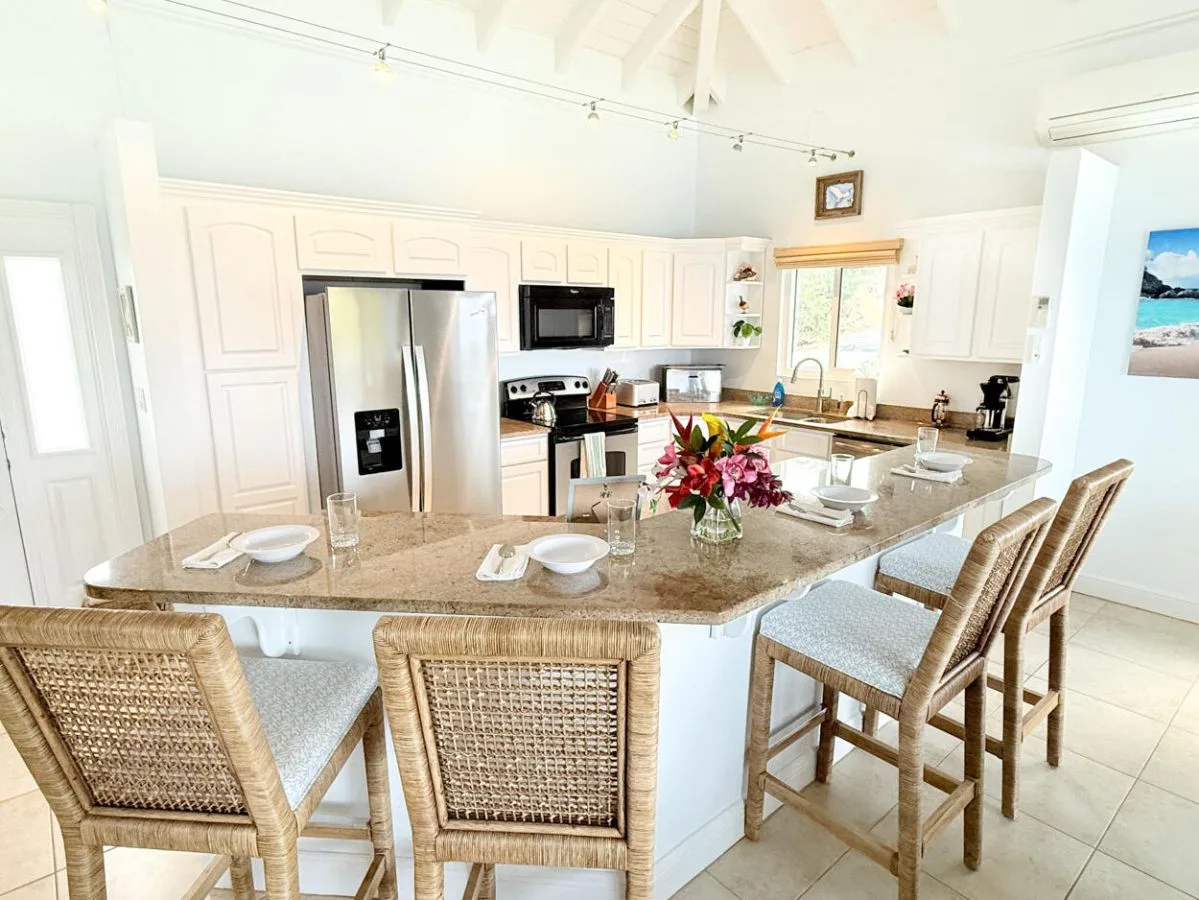 Una cocina luminosa con una isla grande y asientos tejidos.