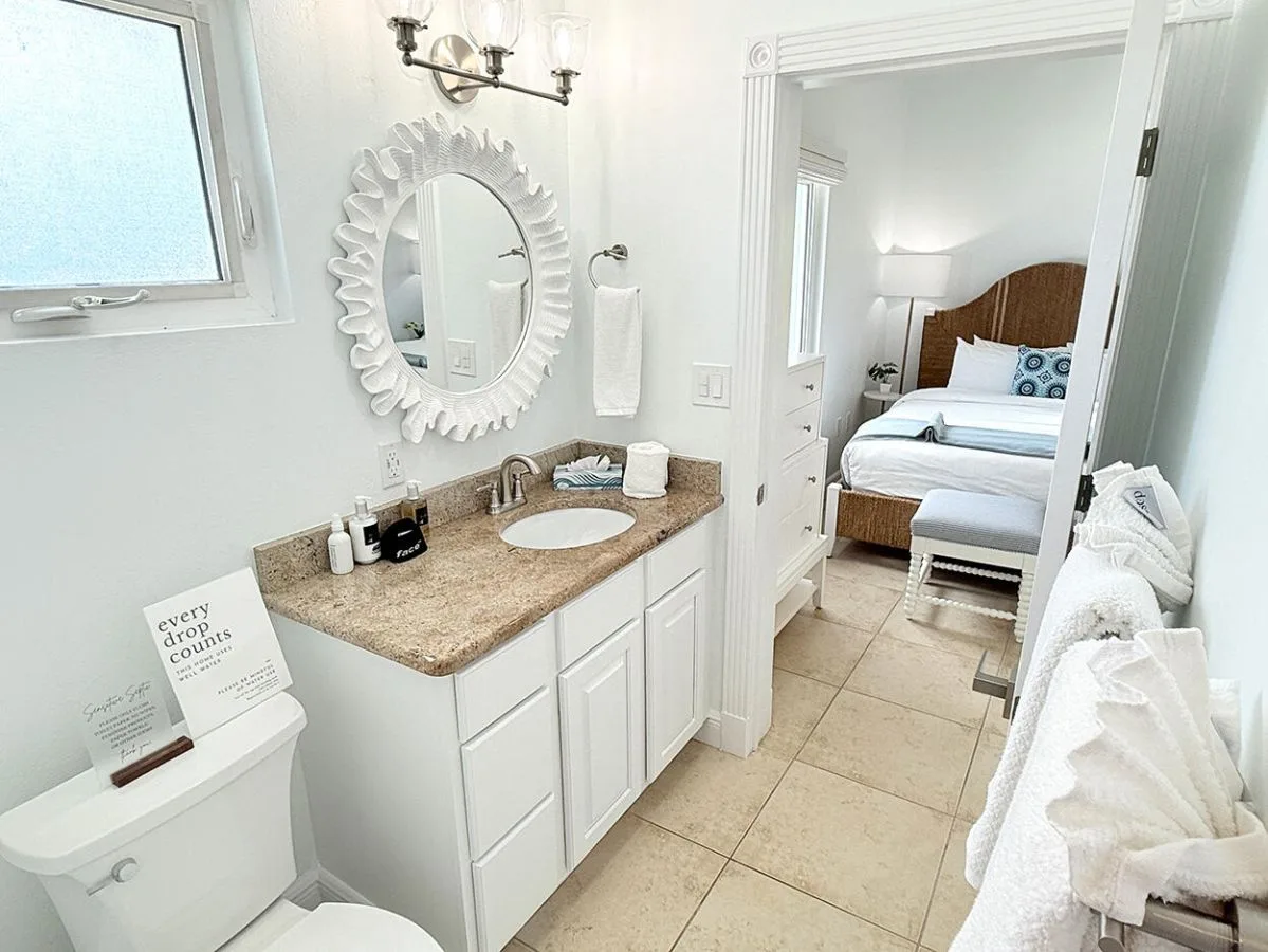Un baño luminoso con tocador y vista al dormitorio contiguo.