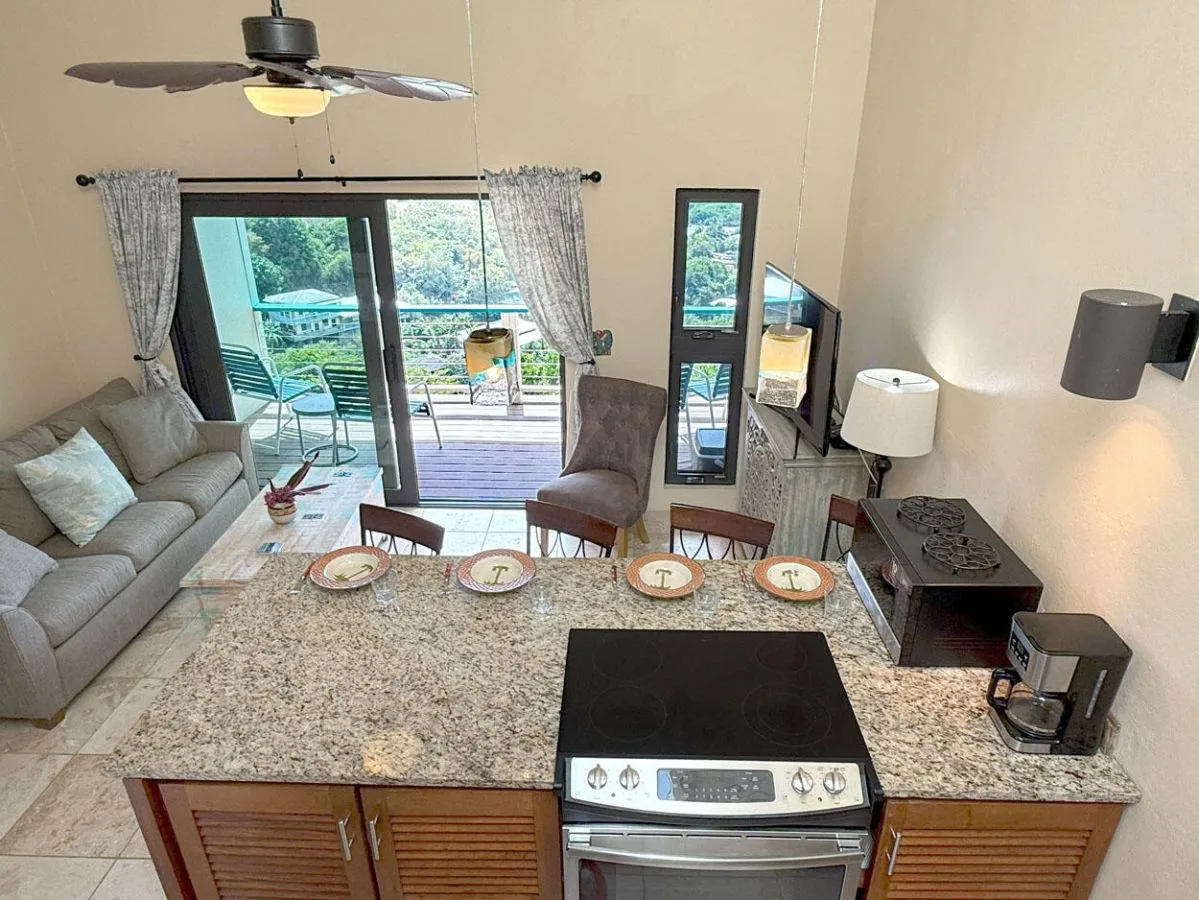 Una sala de estar con una barra de cocina y puertas corredizas de vidrio que dan a un patio.