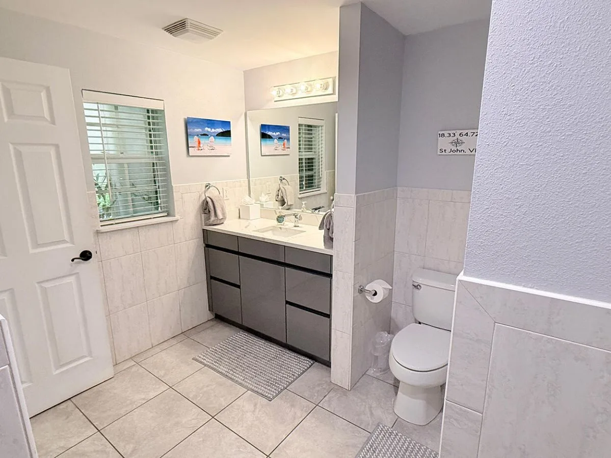 Un baño con lavabo, espejo e inodoro.
