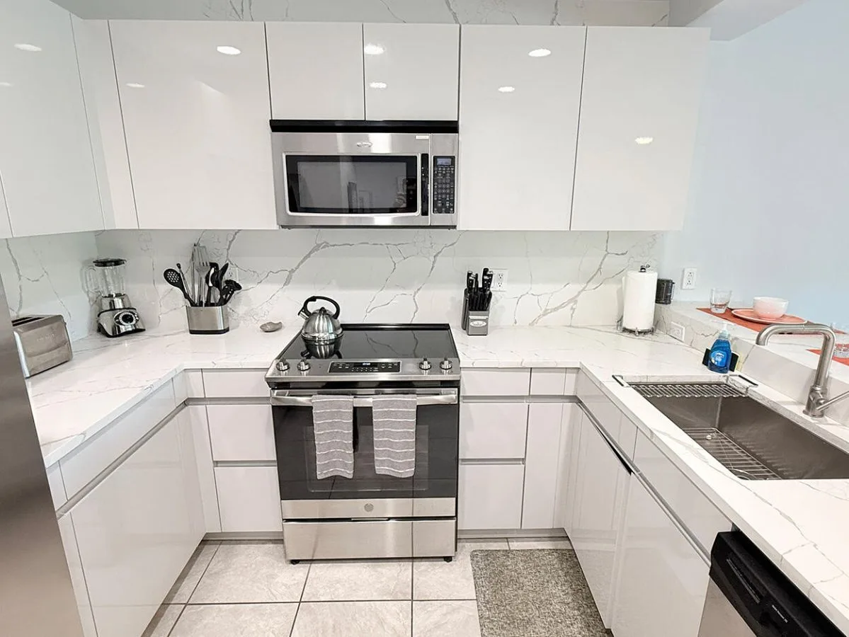 Una cocina moderna y luminosa con gabinetes blancos y electrodomésticos de acero inoxidable.