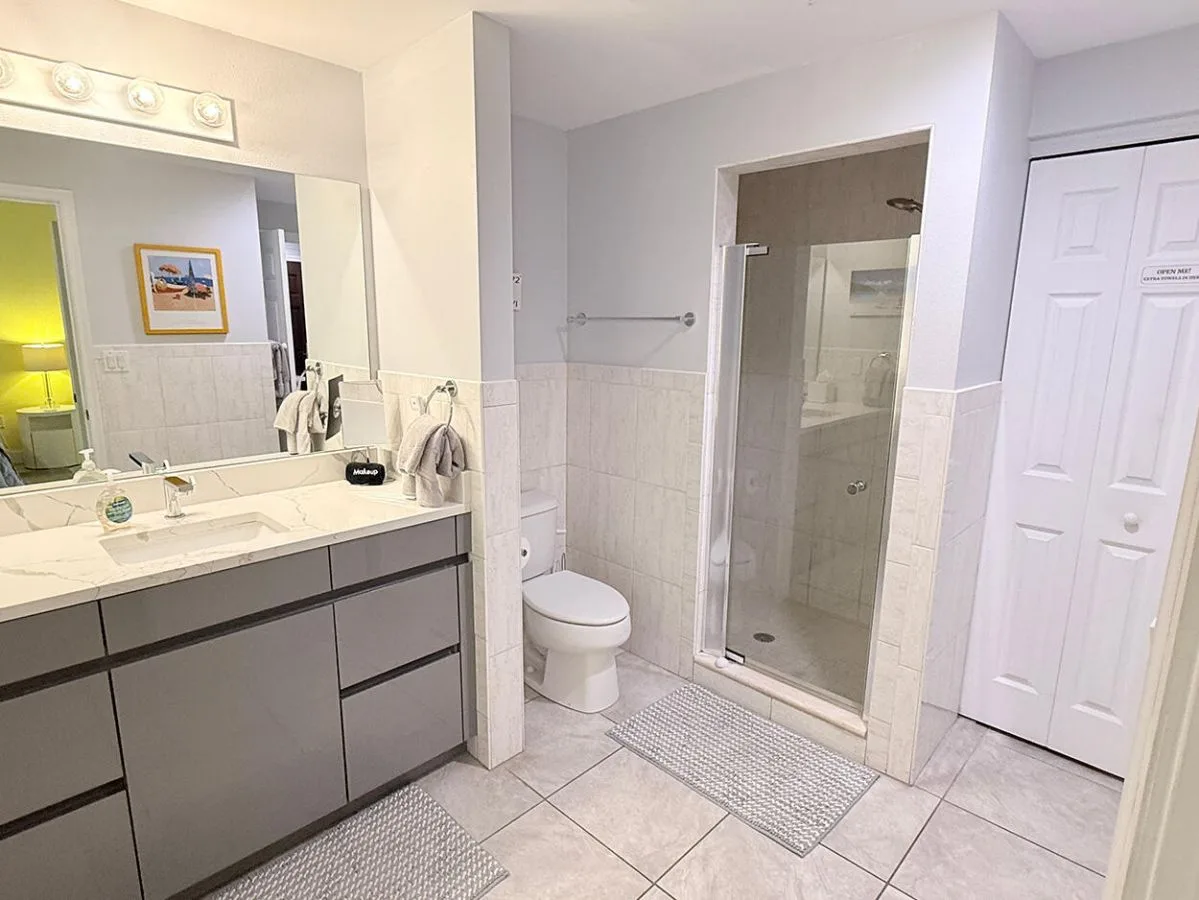 Un baño con lavabo, espejo, inodoro y ducha de vidrio.