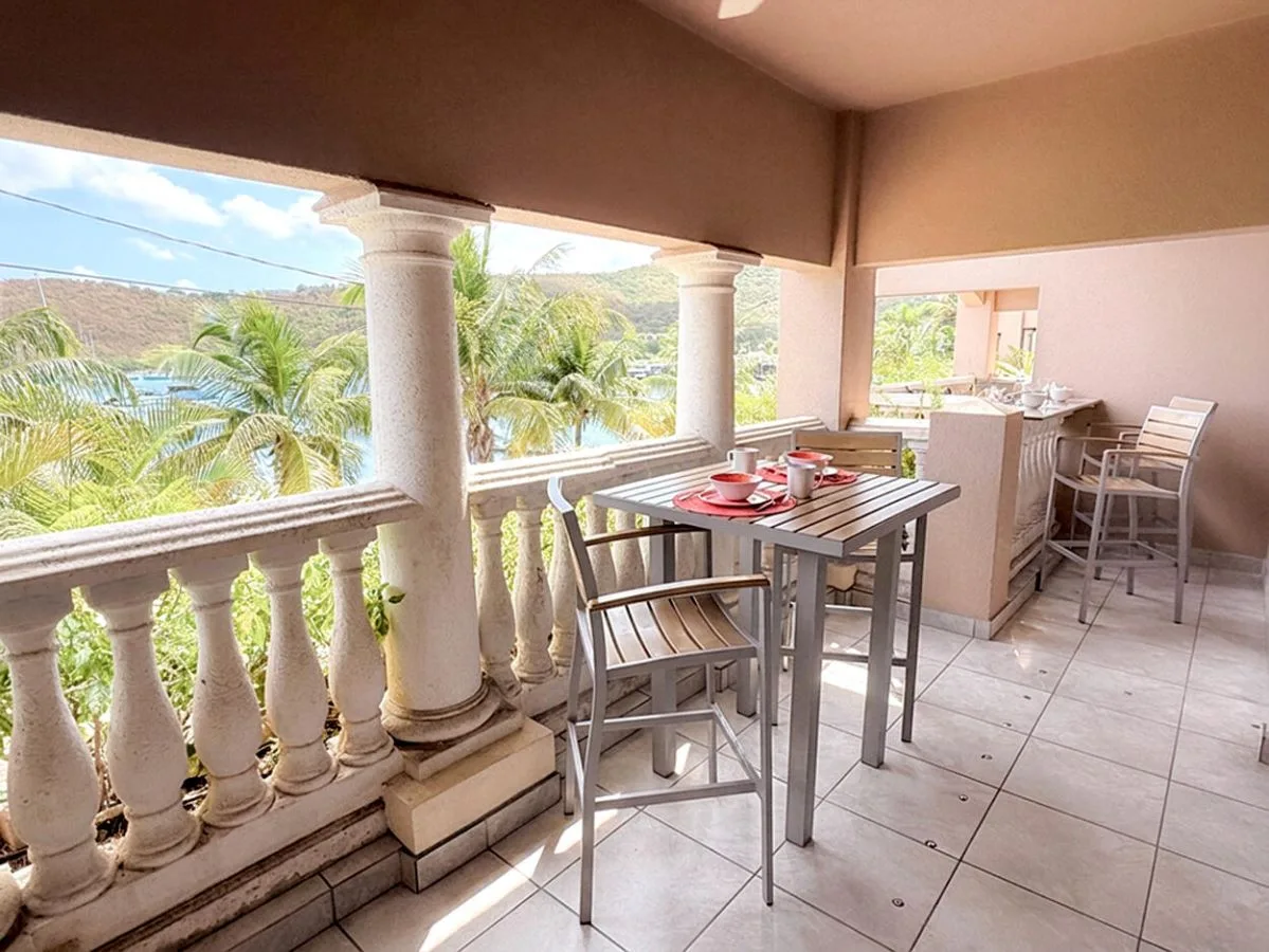 Comedor exterior cubierto con mesa y sillas, con palmeras a la vista.