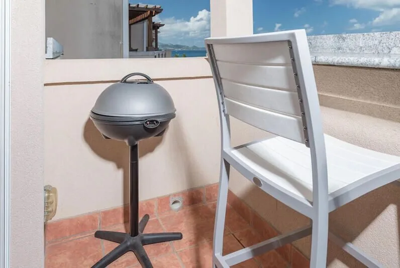 Una terraza en la azotea con una parrilla y asientos al aire libre.