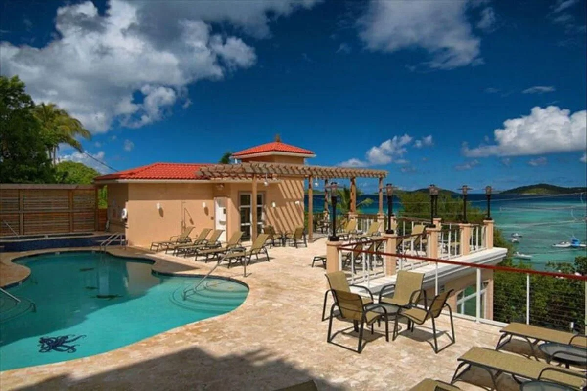 Zona común: Una terraza junto a la piscina tiene asientos y una pérgola con vistas al agua.