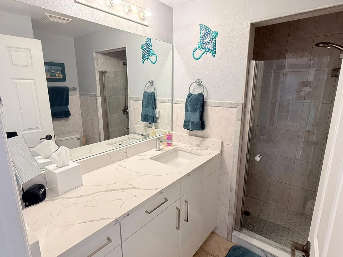 Un tocador de baño con un espejo grande y una ducha de vidrio.