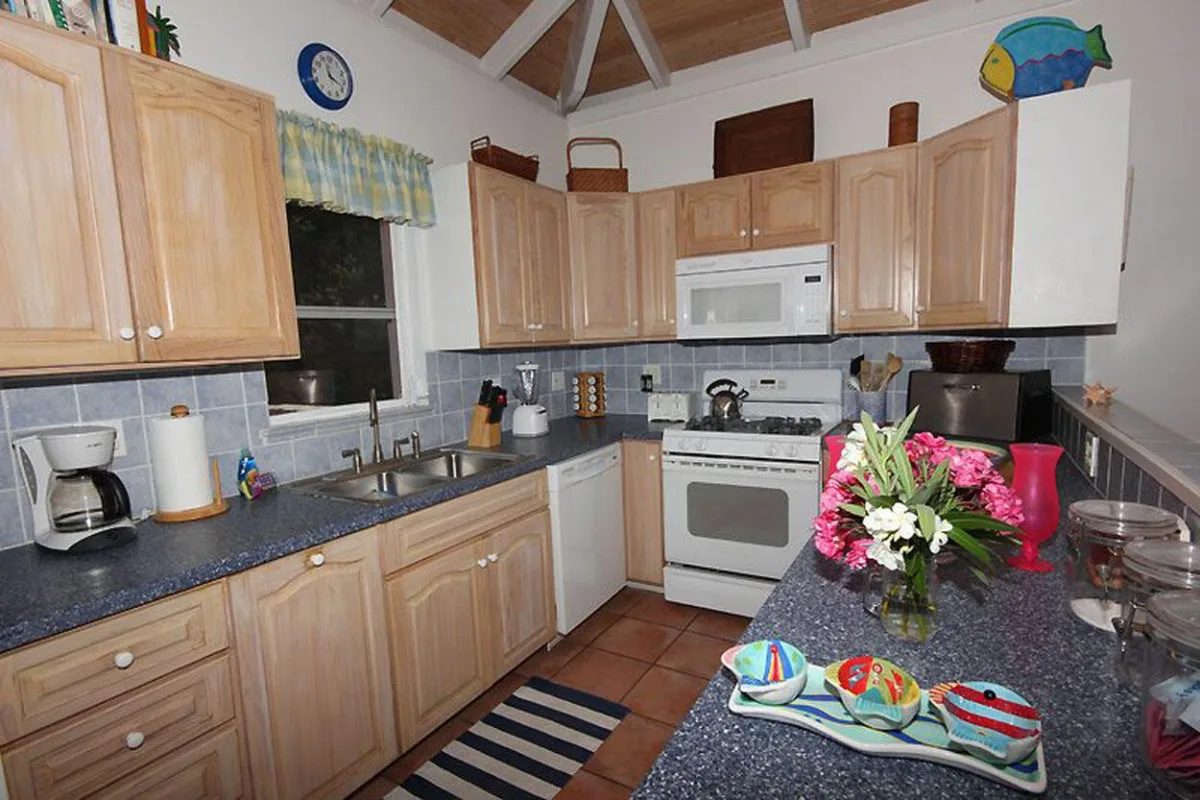 Una cocina con gabinetes de madera, una estufa y flores sobre la encimera.