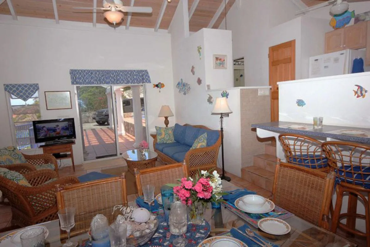 Sala de estar y comedor con asientos, una mesa y una barra de cocina.