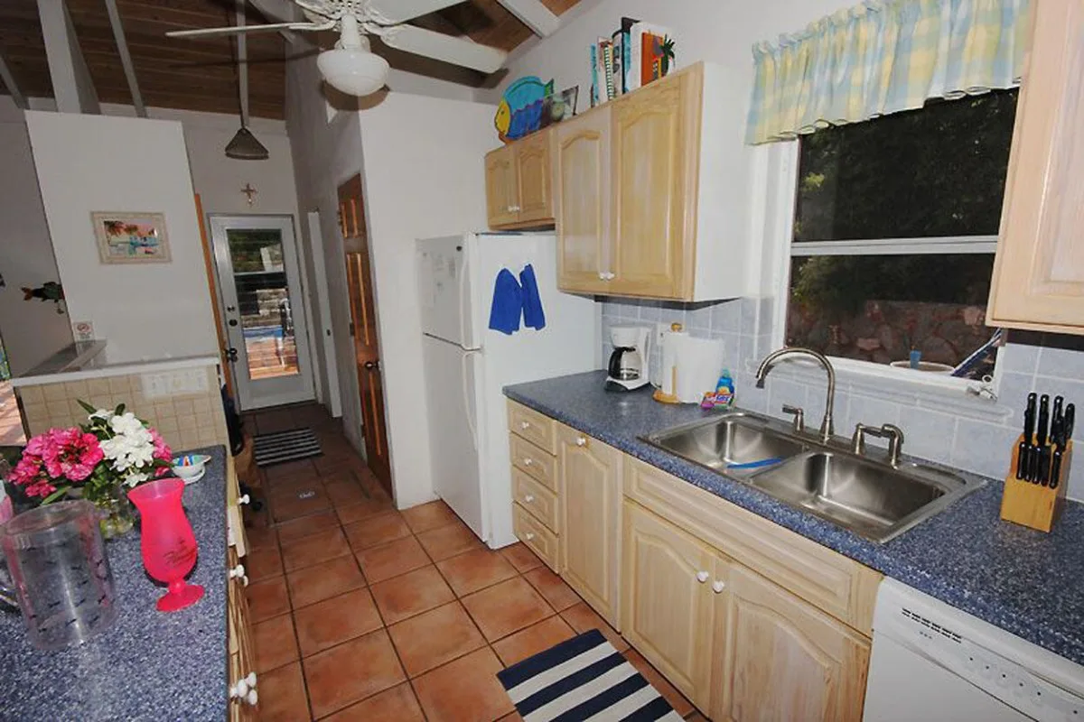 Una cocina con gabinetes de madera, encimeras azules y un fregadero doble.