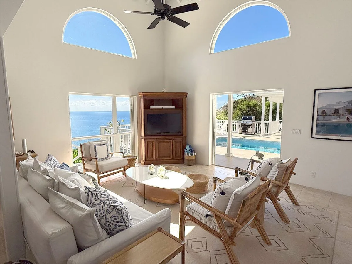 Una sala de estar luminosa con asientos acolchados y grandes ventanas con vistas al agua.
