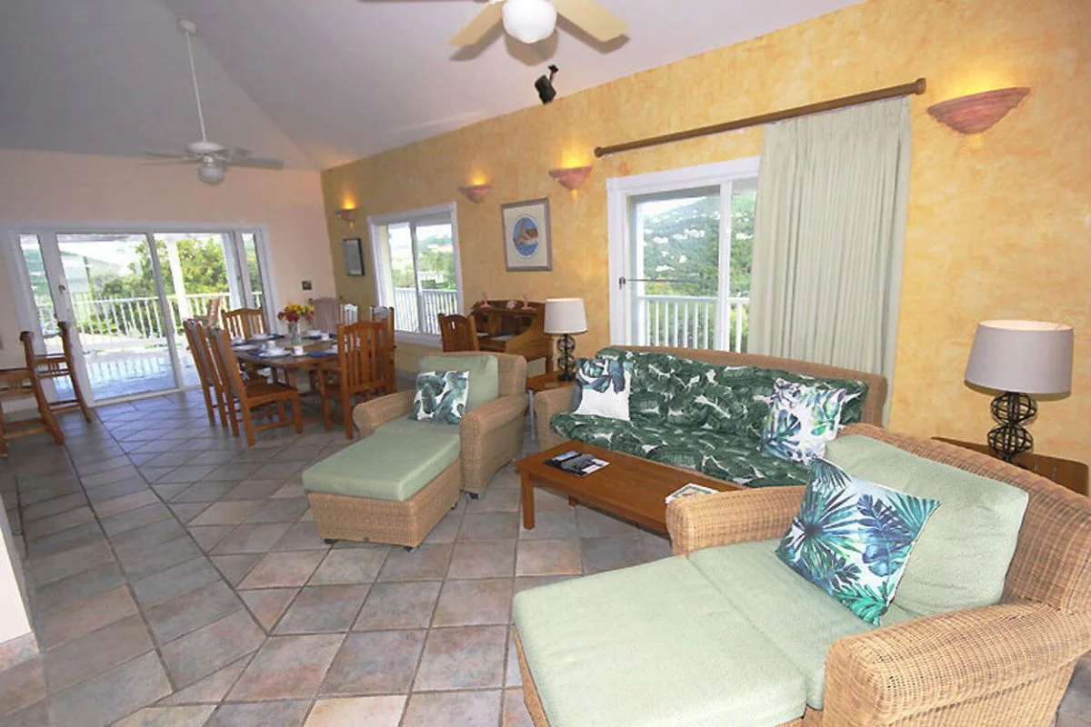 A living and dining area with seating, a wooden table, and sliding glass doors.