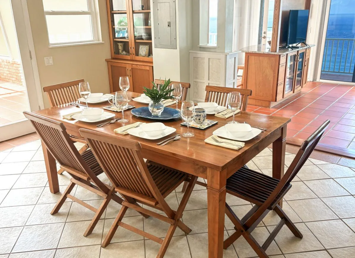 Comedor con una mesa de madera preparada con platos y sillas.